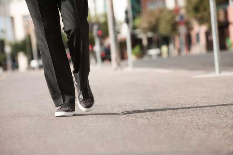 Bottom Half of Mans Body Walking Wearing Pleaded Pants and Sneakers