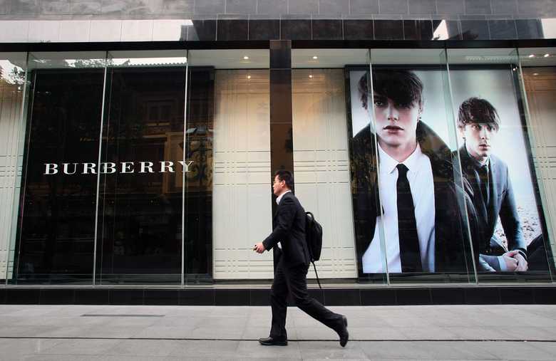 a Burberry store window and a man passing in front of it