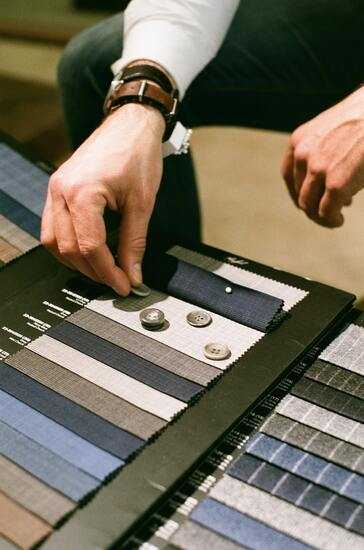 a tailor going over fabrics and buttons for suits