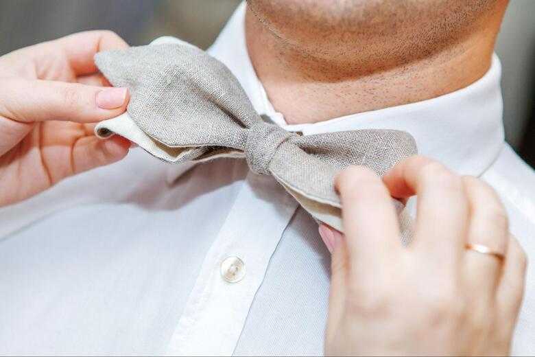 a woman fixing a man's bow tie